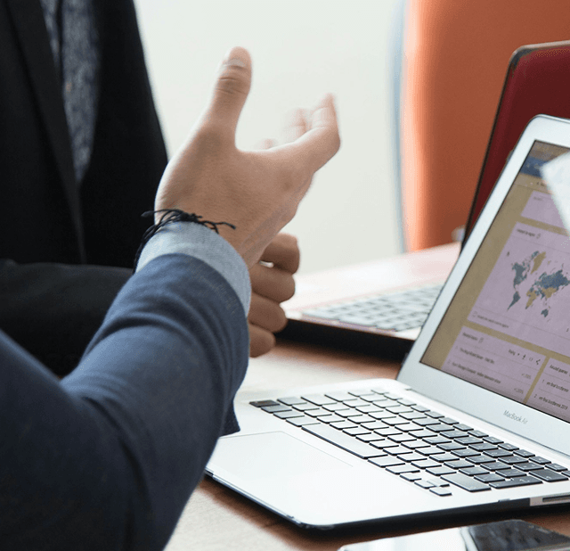 person in business suit gestures at open laptop